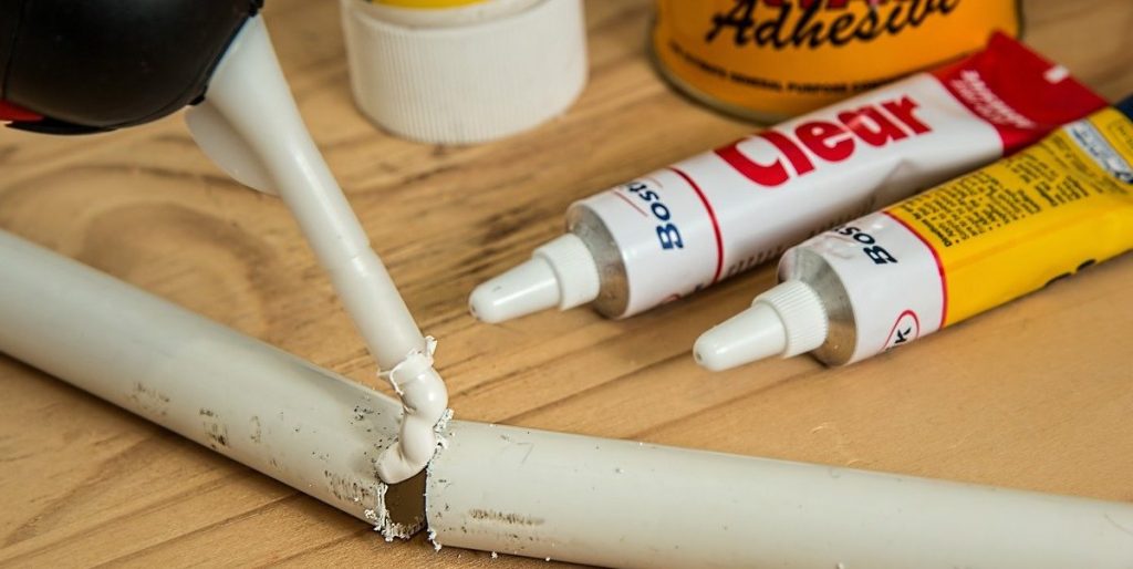 Pipework being repaired by glue on a wooden table