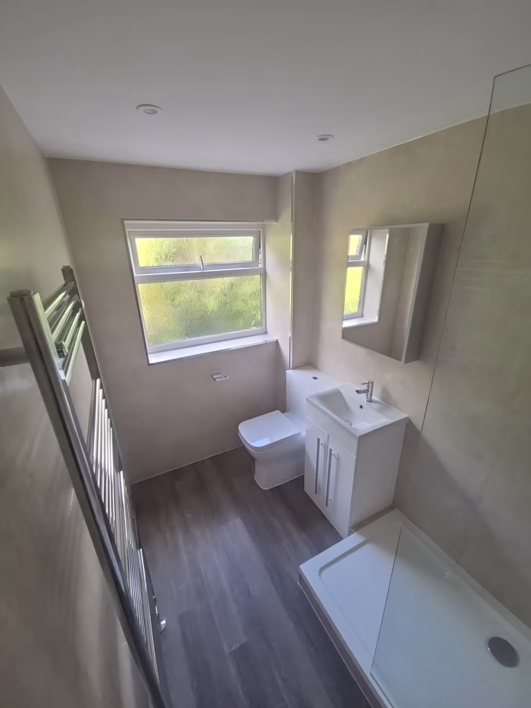Modern bathroom renovation in Exeter with walk-in shower, chrome fittings, and waterproof wall panels.