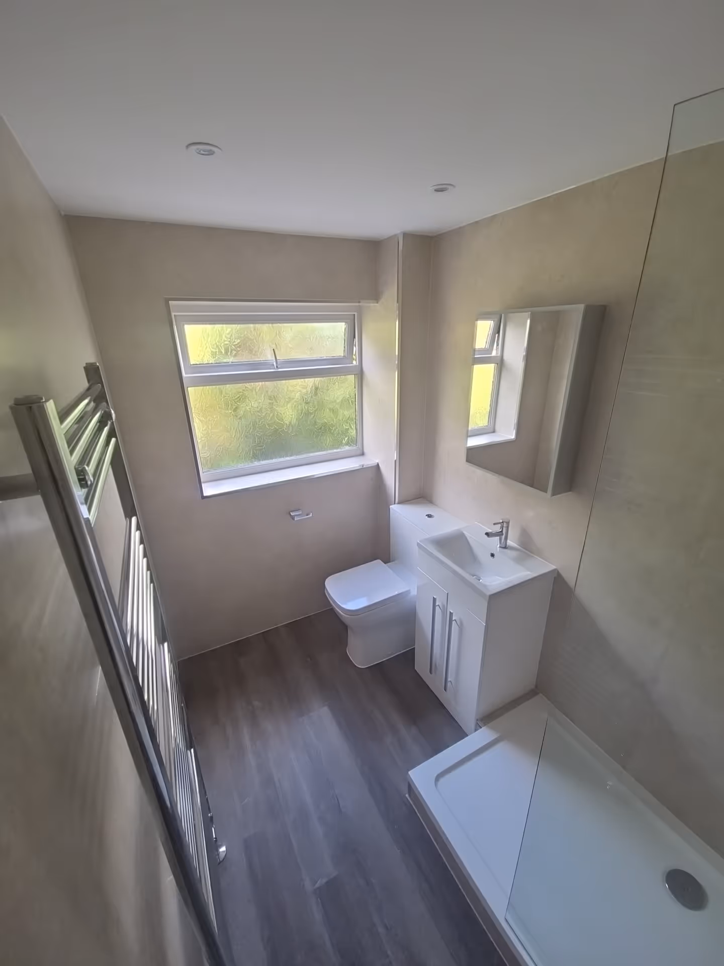Modern bathroom renovation in Exeter with walk-in shower, chrome fittings, and waterproof wall panels.